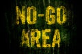 Ã¢â¬ÅNo-Go AreaÃ¢â¬Â warning sign in yellow letters painted over dark grungy concrete wall with moss